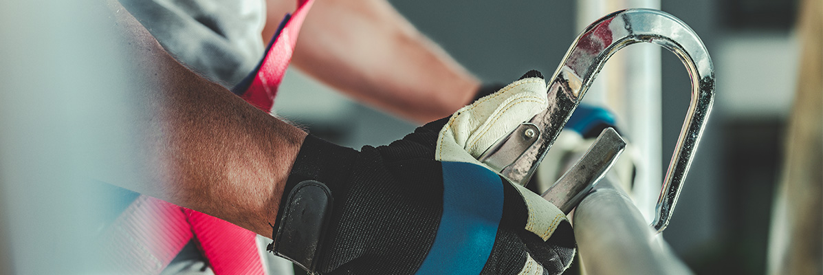 Gros plan sur un mousqueton de harnais de sécurité attaché à une structure métallique.