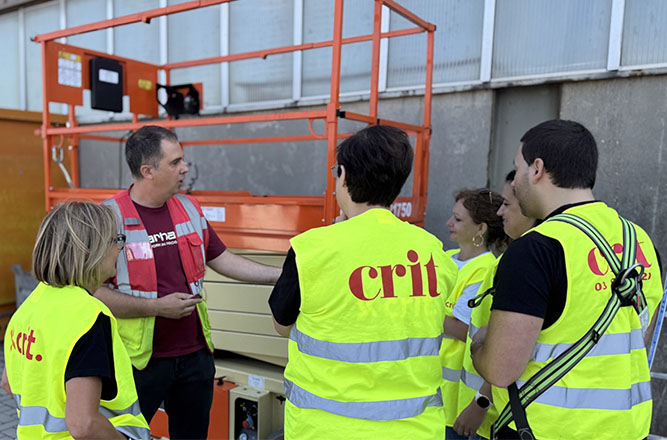 Formateur expliquant l’utilisation d’une nacelle élévatrice à un groupe de stagiaires en gilets haute visibilité CRIT lors d’une formation PEMP