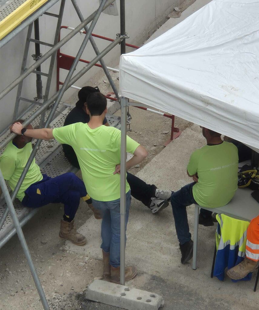 Discussion entre travailleurs autour d’un atelier de prévention des chantiers sur chantier, en zone sécurisée