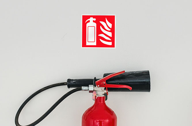 Extincteur rouge fixé au mur sous un pictogramme incendie, symbole de la formation équipier de première intervention