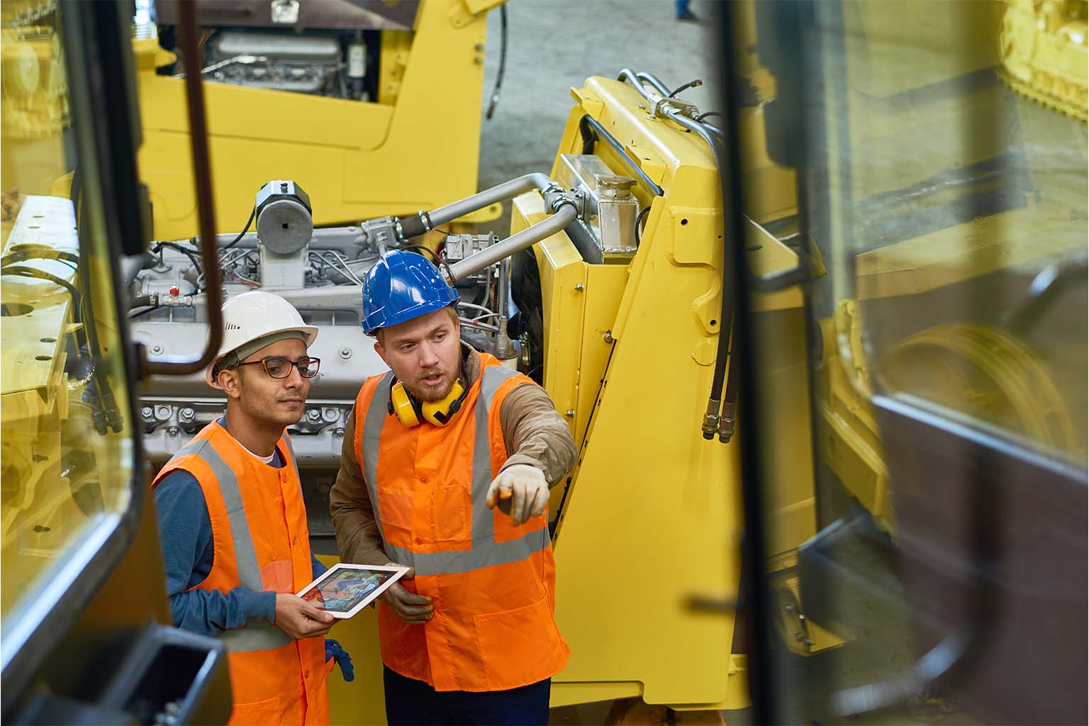 Deux techniciens discutant lors d’une inspection VGP sur un engin de chantier.