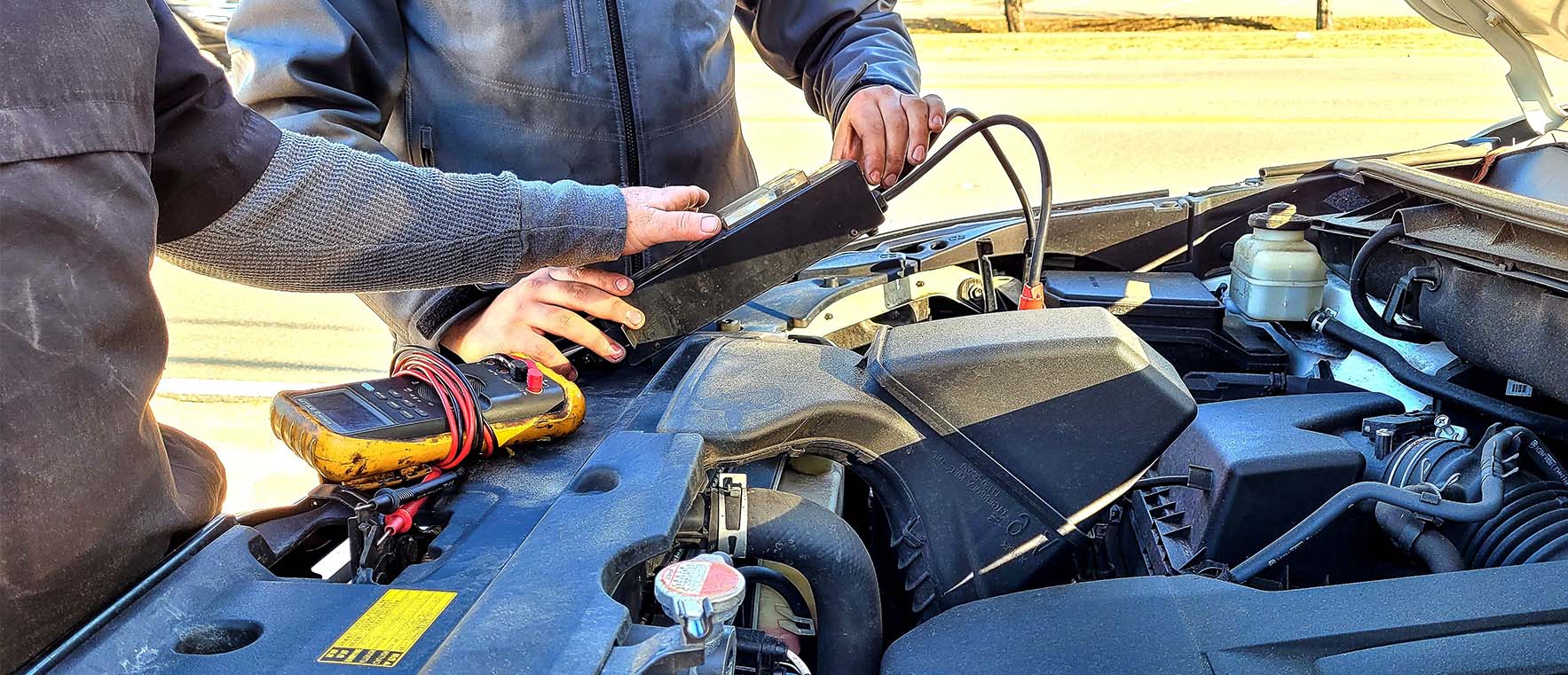Mécaniciens effectuant un diagnostic automobile sous le capot.