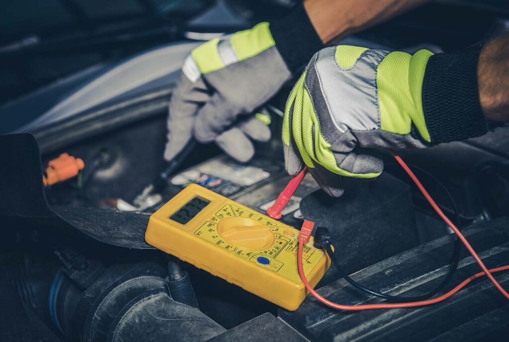 Mesure de tension sur une batterie de voiture avec un multimètre.