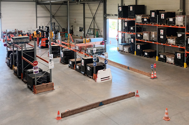 Vue d’ensemble d’un entrepôt industriel avec rayonnages métalliques, racks de stockage et zones de circulation matérialisées pour la gestion des flux logistiques