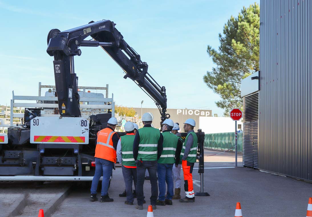 Formation grue : un formateur encadre un groupe de stagiaires autour d’un camion équipé d’une grue auxiliaire pendant un exercice pratique.