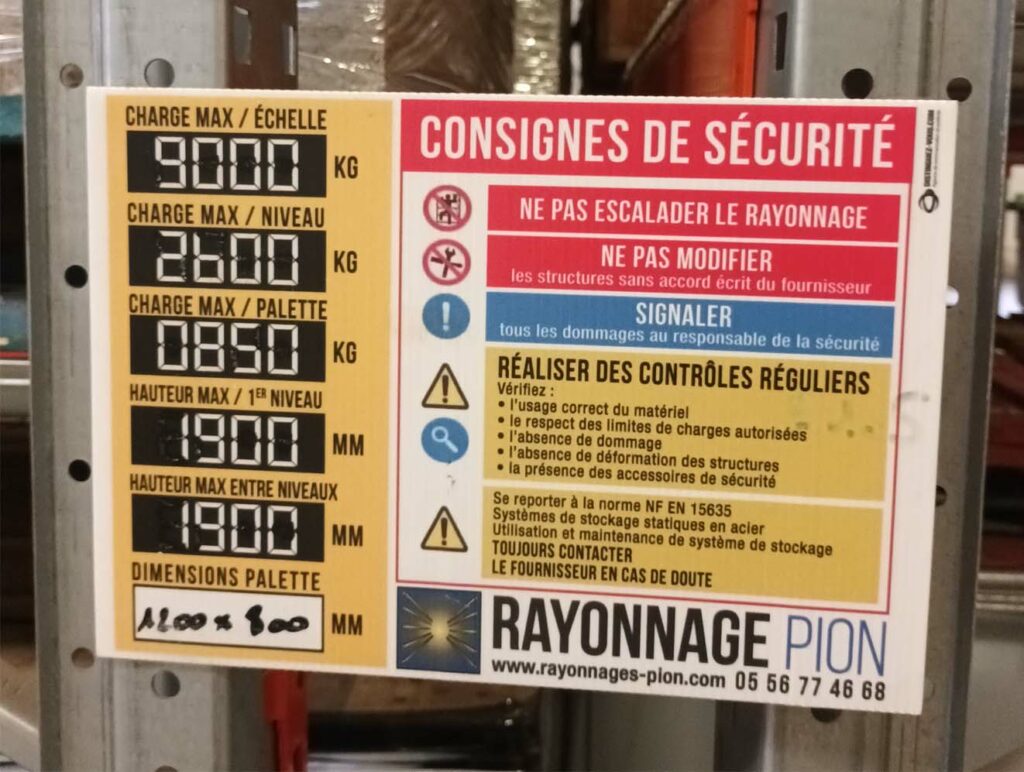 Plaque de charge sur un rack de stockage palletier en rayonnage métallique indiquant les limites de charge et consignes de sécurité