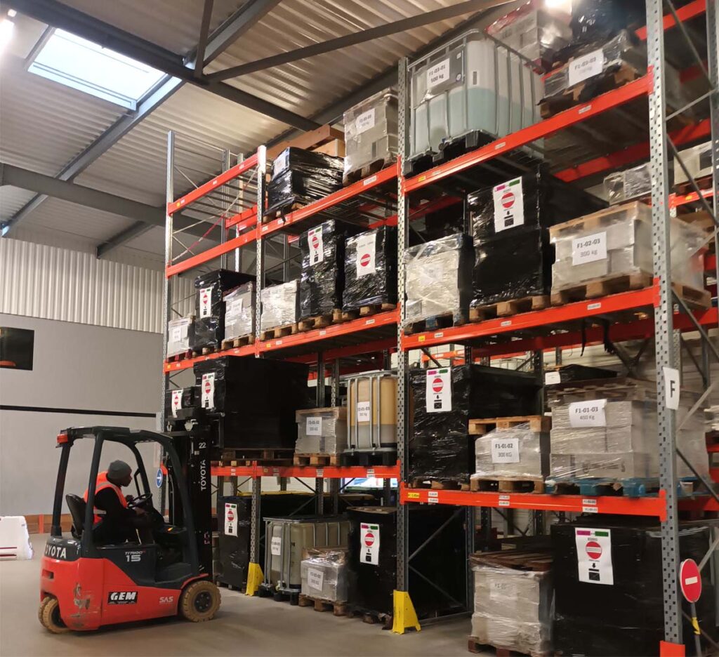 Cariste manœuvrant un chariot élévateur devant un rayonnage métallique de type palletier dans un entrepôt logistique