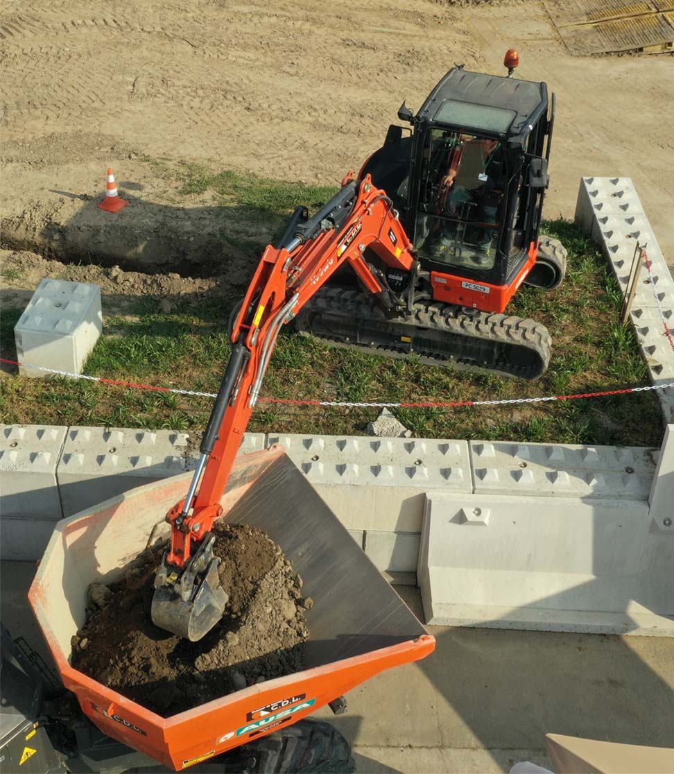 Pelle hydraulique engin compact R.482 catégorie A chargeant un moto-basculeur