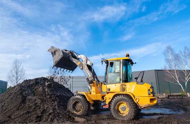 Chargeuse sur pneus jaune en train de déverser de la terre sur un chantier
