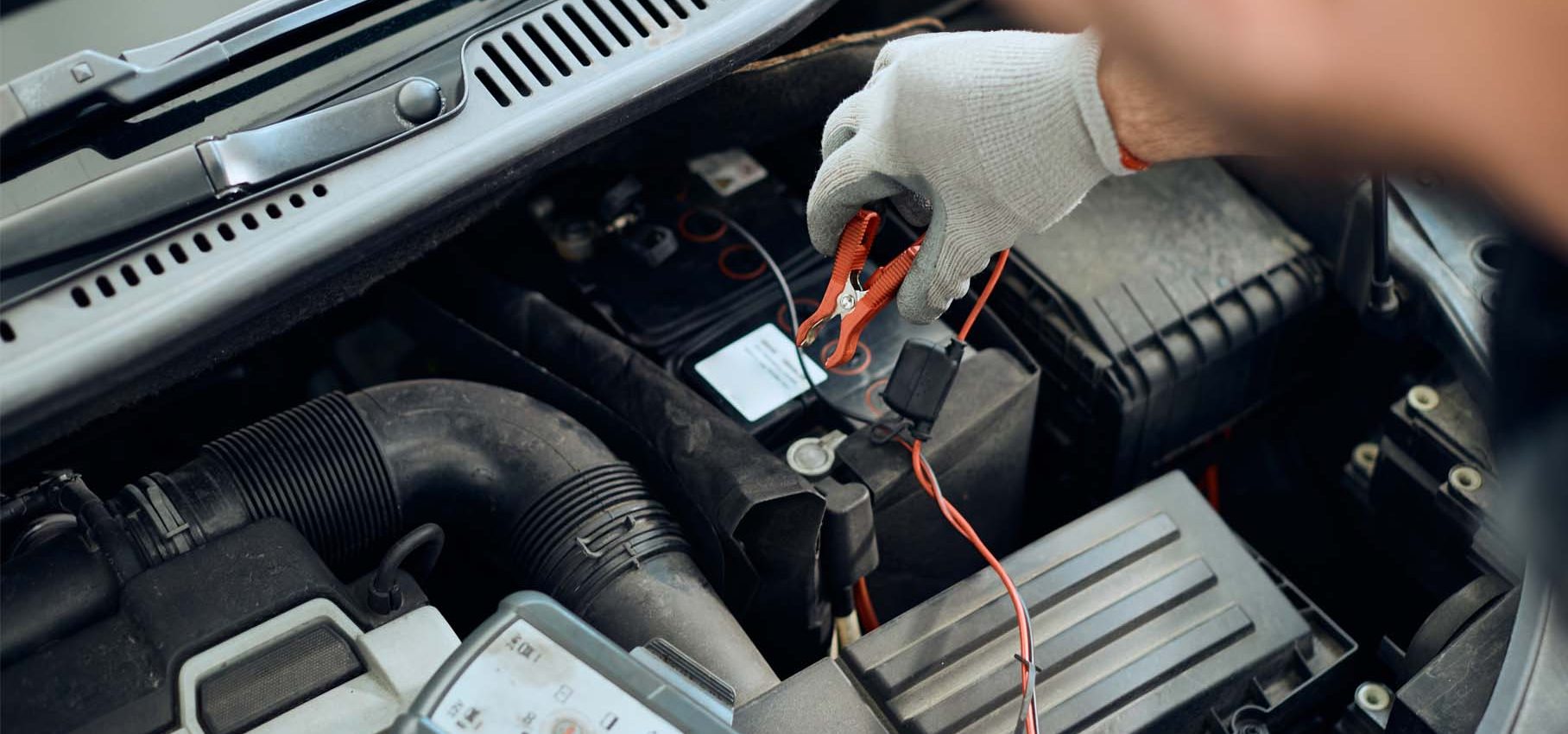 Technicien effectuant une mesure électrique sous tension sur un véhicule à l'aide d'un multimètre, dans le cadre d'une intervention TST IEVE