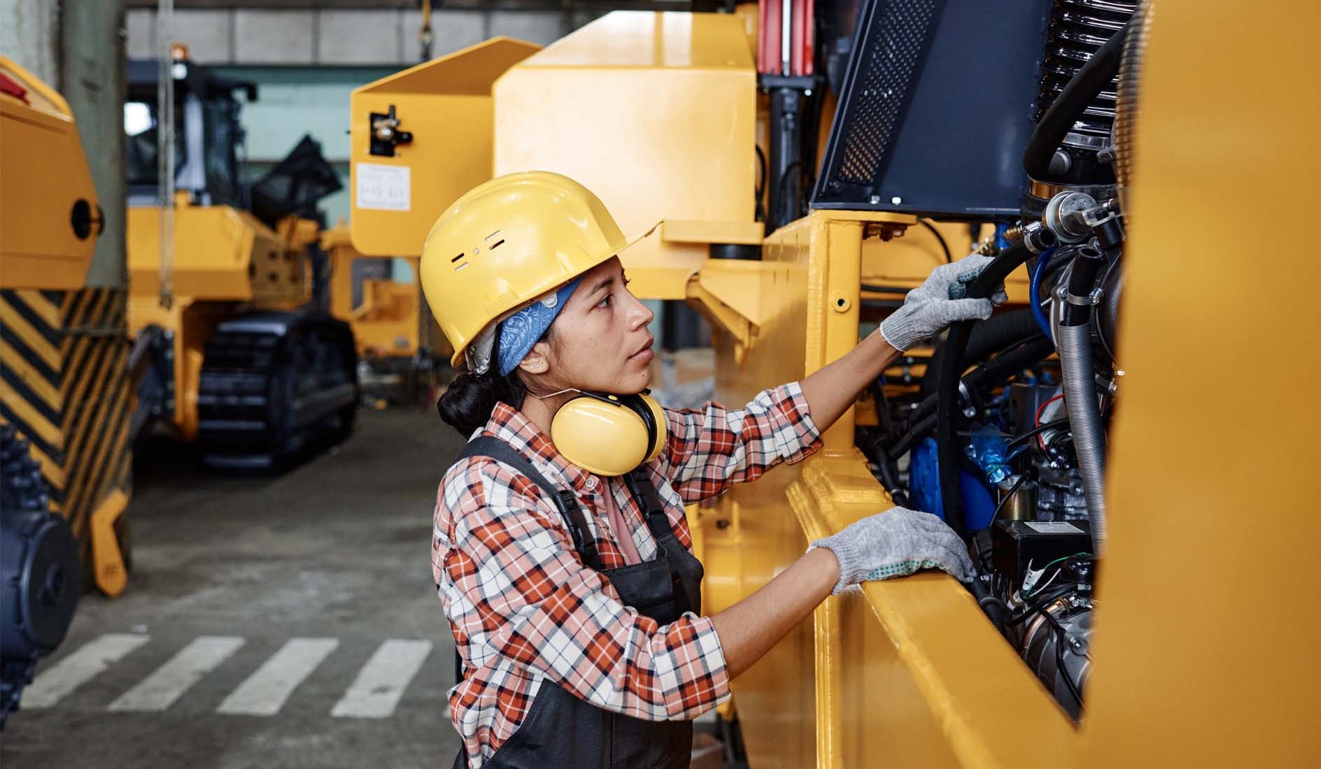 Technicienne effectuant une vérification générale périodique (VGP) sur un engin de chantier